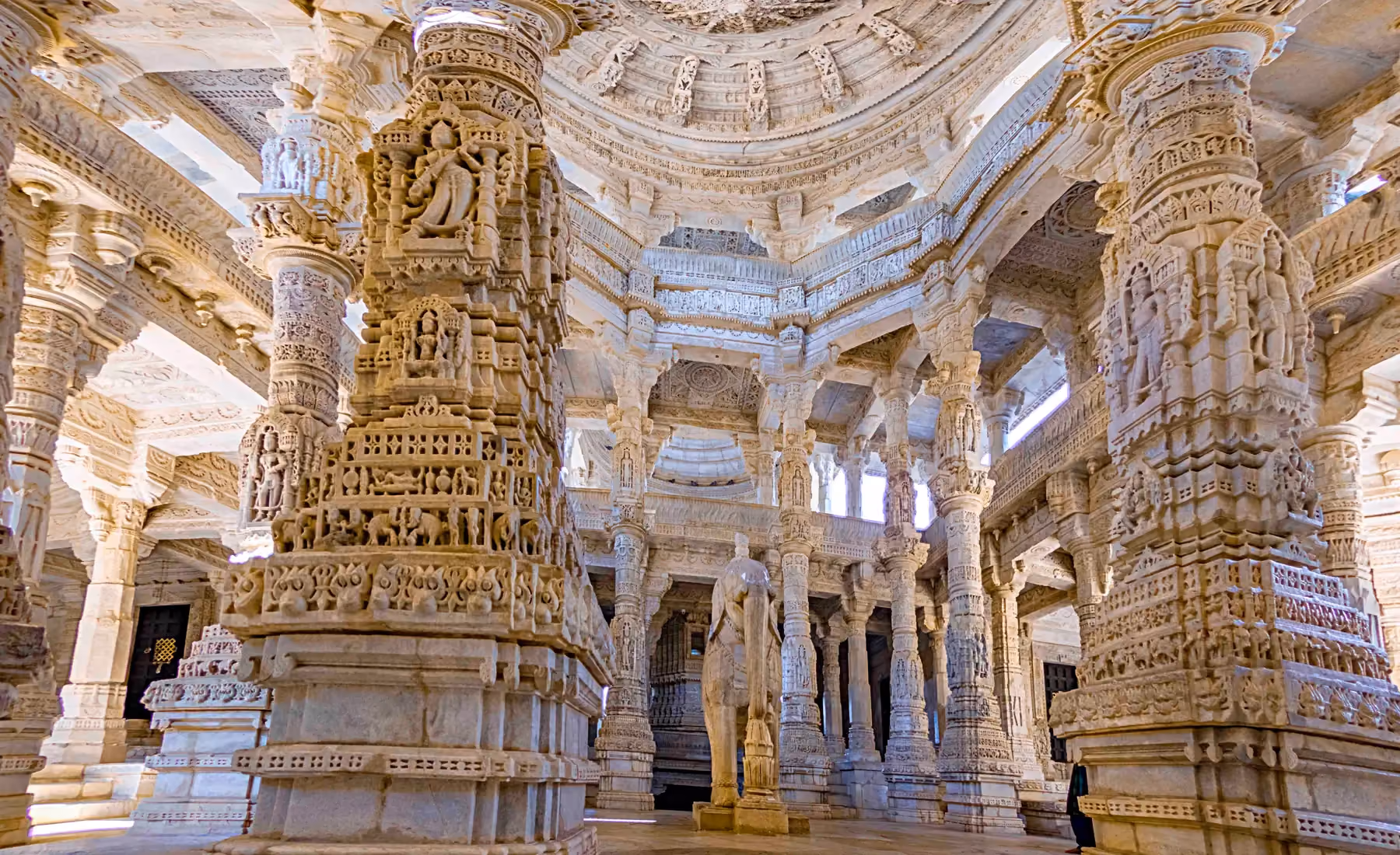 Carved white marble pillars filling the interior hall of the Ranakpur Jain temple, each one different